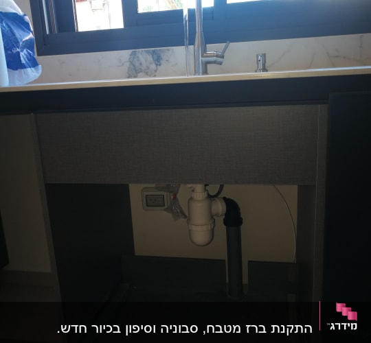 כיור מטבח עם ברז וצנרת מתחת לארון